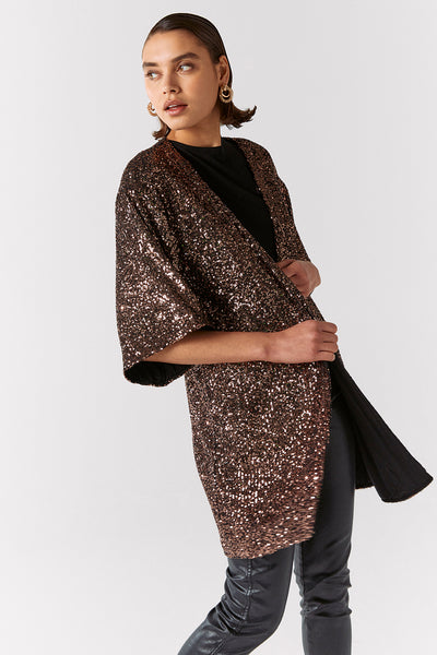 Scamp and Dude Rose Gold Sequin Kimono | Model wearing gold sequin kimono with black jeans and top against white background