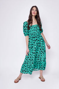 A lady wearing a green with black leopard and lightning bolt print shirred midi dress with blouson sleeves
