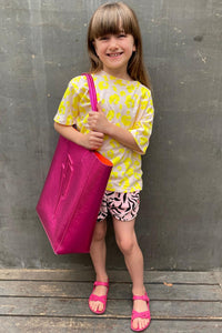 Scamp and Dude | Kids Blush with Neon Yellow Leopard T-Shirt | Young girl wearing a light pink and yellow leopard print top with leopard print shorts holding a pink tote bag