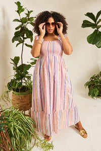 A lady in a Scamp & Dude pink with rainbow lurex sundress with blush pink oversized &