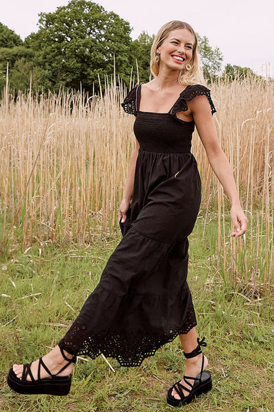 Scamp and Dude Black Maxi Dress | Model in a wheat field wearing a black maxi dress with black sandals 