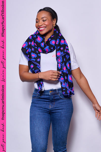 Scamp and Dude Black, Pink and Blue Leopard Print Scarf | Model smiling wearing a leopard print scarf with white top and blue jeans