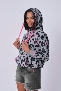 A lady pulling on the drawstrings of her stone grey with black leopard and lightning bolt cowl neck hoodie