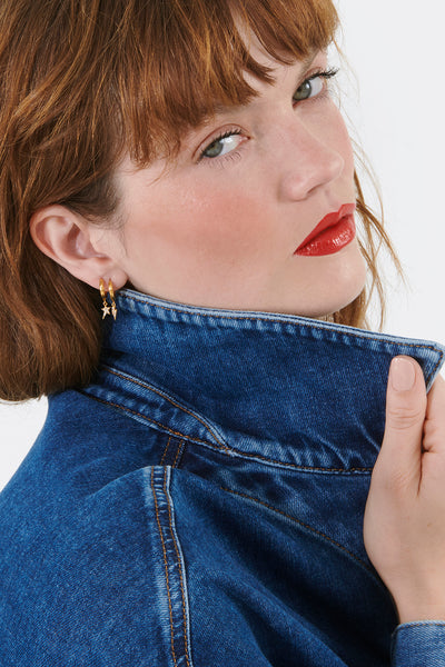 Scamp & Dude x Rachel Jackson Gold Plated Huggie Hoops with Champagne Pavé Detailed Lightning Bolt & Star Charms | Model wearing a denim shirt with gold star earrings