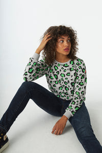 Scamp and Dude Pale Grey with Neon Green and Black Snow Leopard Sweatshirt | Model sat down against white background wearing a pale grey and green leopard jumper and dark wash jeans