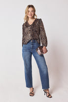 Scamp & Dude Neutral Milano Leopard Printed Cord Collared Blouse | Model wearing a neutral leopard long sleeve top with blue straight leg jeans and black heels.