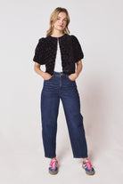 Scamp & Dude Black Heart & Bolt Burn Out Velvet Top | Model wearing a black velvet burn out top with a pair of barrel leg jeans and navy cheetah print trainers.
