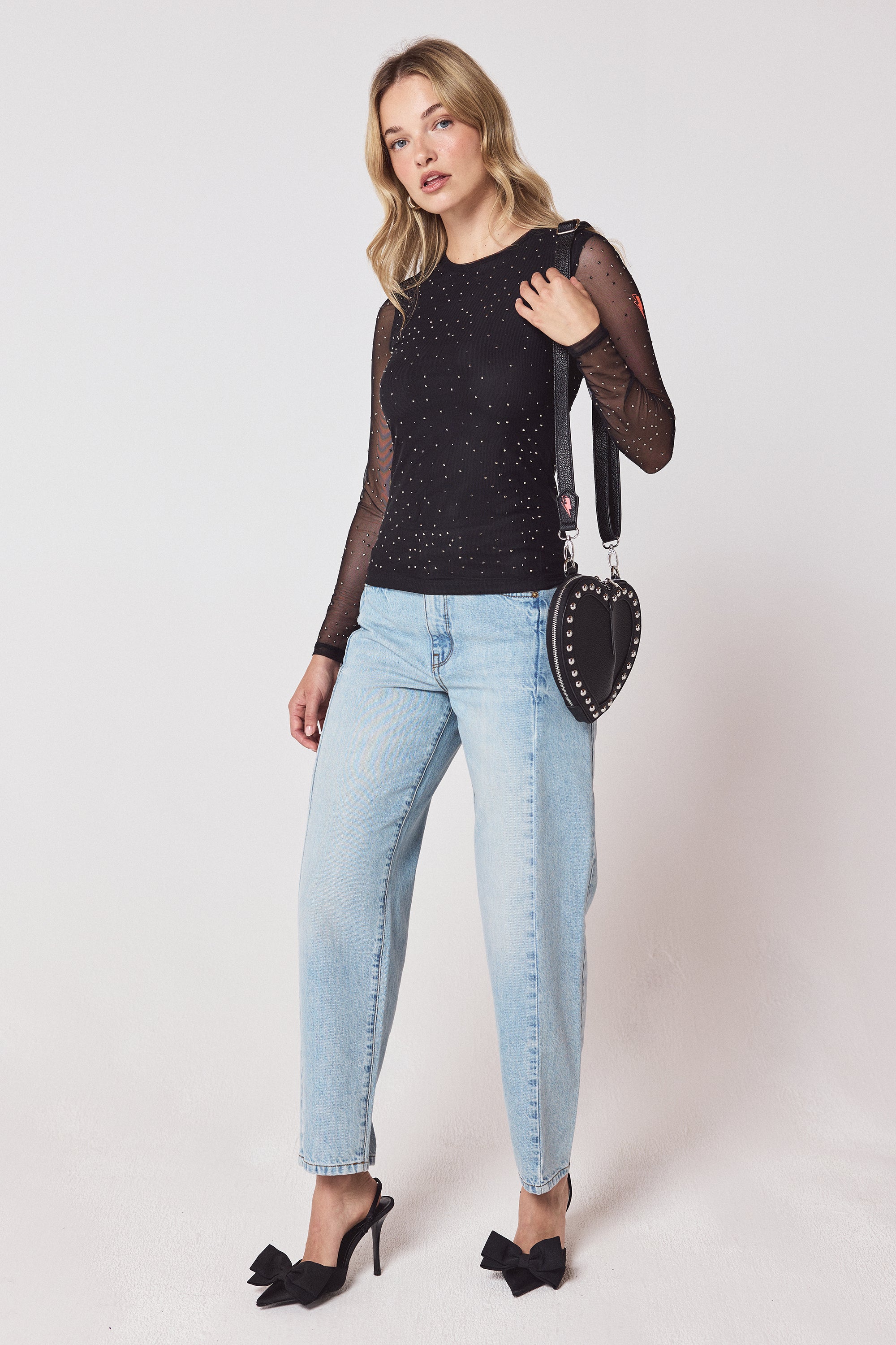Scamp & Dude Black Embellished Mesh Top | Model wearing a black mesh top with pale blue jeans and black bow heels.