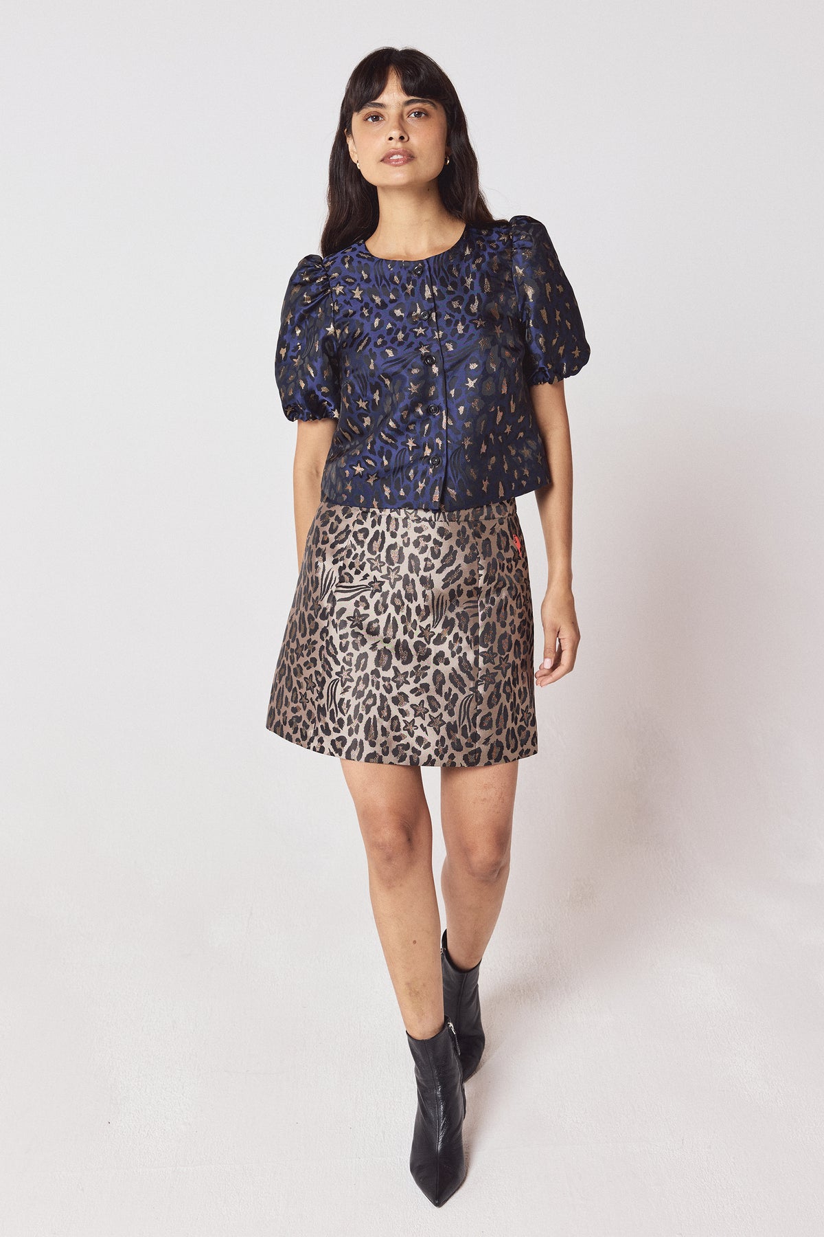 Scamp & Dude Navy Star Leopard Jacquard Top | Model wearing a navy leopard jacquard top with a gold mini skirt and black heeled boots.