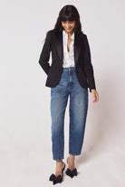 Scamp & Dude Black Ultimate Tux Jacket | Model wearing a black tux jacket with a white star print shirt and blue jeans. Worn with black bow high heels.