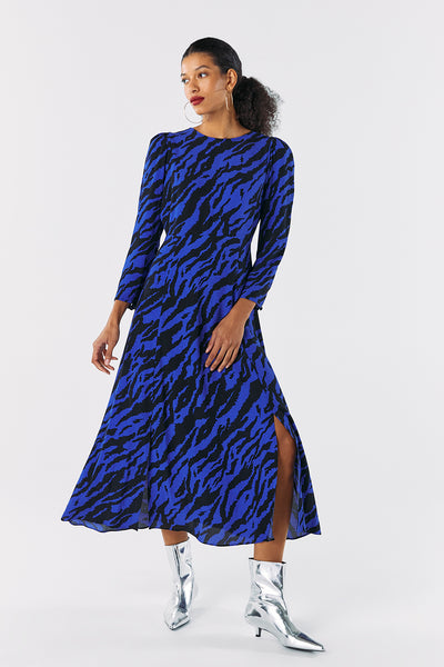 Scamp and Dude Blue with Black Shadow Tiger Split Hem Midi Dress | Model with hair in low pony tail wearing a long blue dress with black zebra print and silver heeled boots