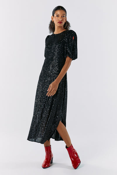 Scamp and Dude Black Sequin Puff Sleeve Midi Dress | Model with silver hoop earrings wearing a long sequin black dress with red heeled boots