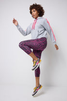 Scamp and Dude Grey with Pink Leopard Ray 7/8 Length Active Leggings | Model wearing a grey hoodie with a pair of grey and pink leopard ray leggings. Worn with trainers.