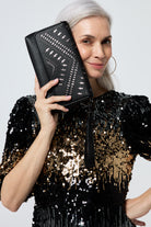 Scamp and Dude Black with Pewter Lightning Bolt Laser Cut Clutch Bag | Model wearing a sequin short dress paired with a black laser cut clutch bag.