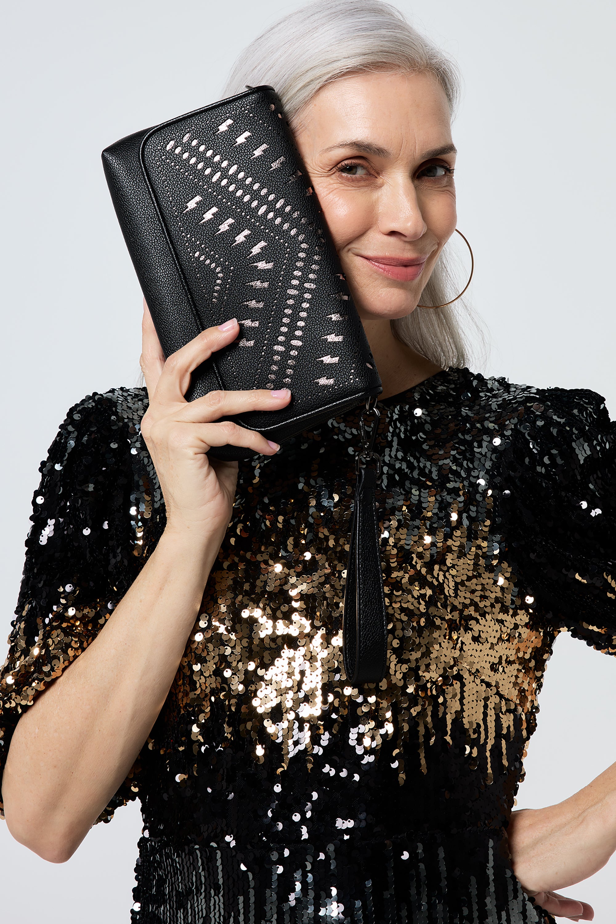Scamp and Dude Black with Pewter Lightning Bolt Laser Cut Clutch Bag | Model wearing a sequin short dress paired with a black laser cut clutch bag.