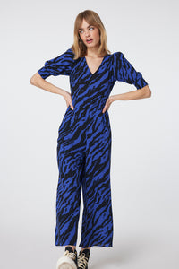 Scamp and Dude Electric Blue with Black Shadow Tiger V-Neck Jumpsuit | Model wearing blue jumpsuit with hands on her hips