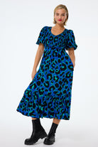 Scamp and Dude Blue with Green and Black Mega Leopard Shirred Puff Sleeve Midi Dress | Model wearing a blue shirred puff sleeve midi dress with green and black leopard print.