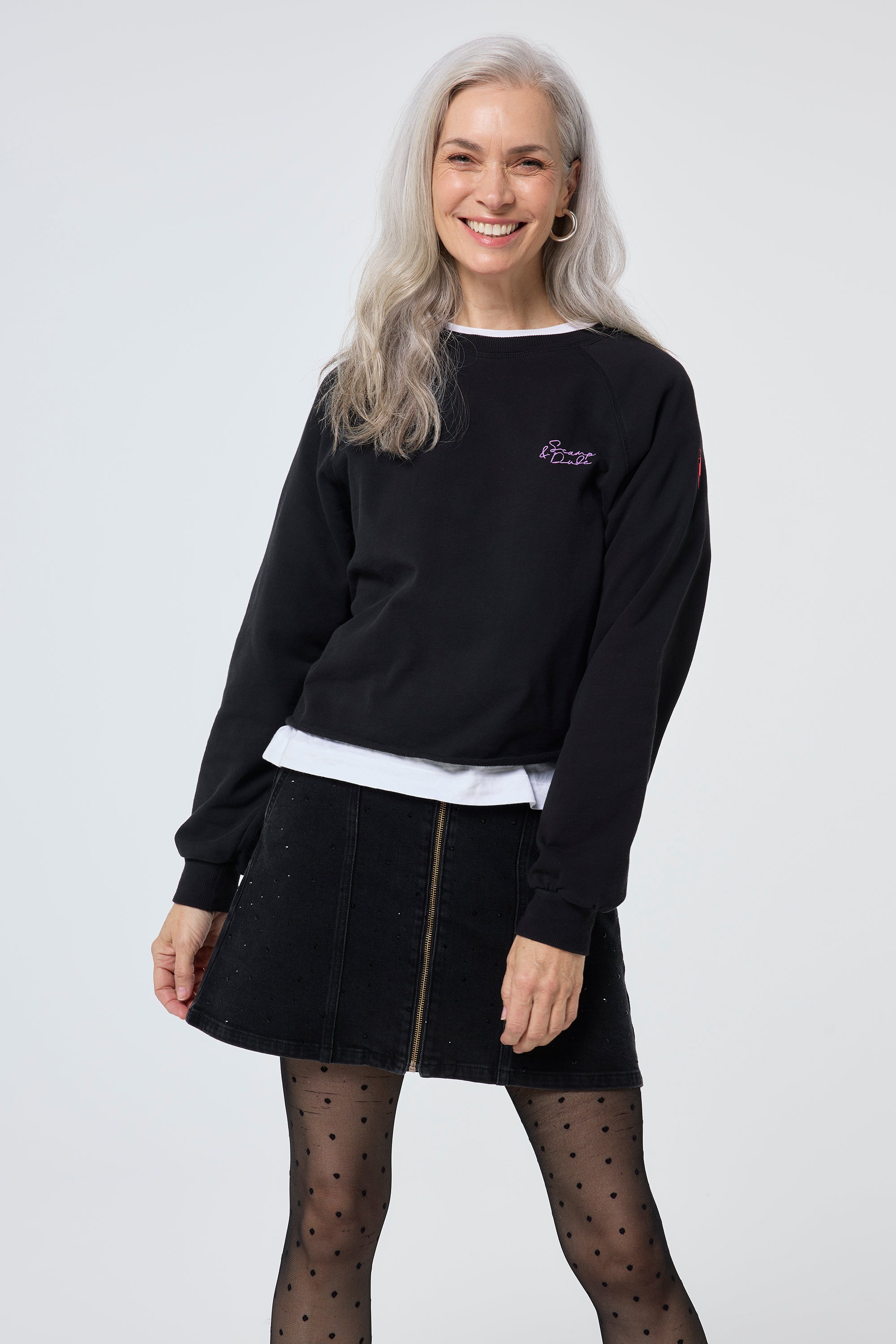 Scamp and Dude Washed Black Cropped Sweatshirt | Model wearing a denim mini skirt with a white t shirt and black cropped sweatshirt.