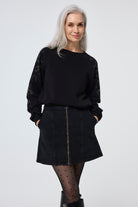 Scamp and Dude Black with Silver Studded Leopard Oversized Tunic | Model wearing a black denim mini skirt with a black tunic sweatshirt with animal print studded detail.