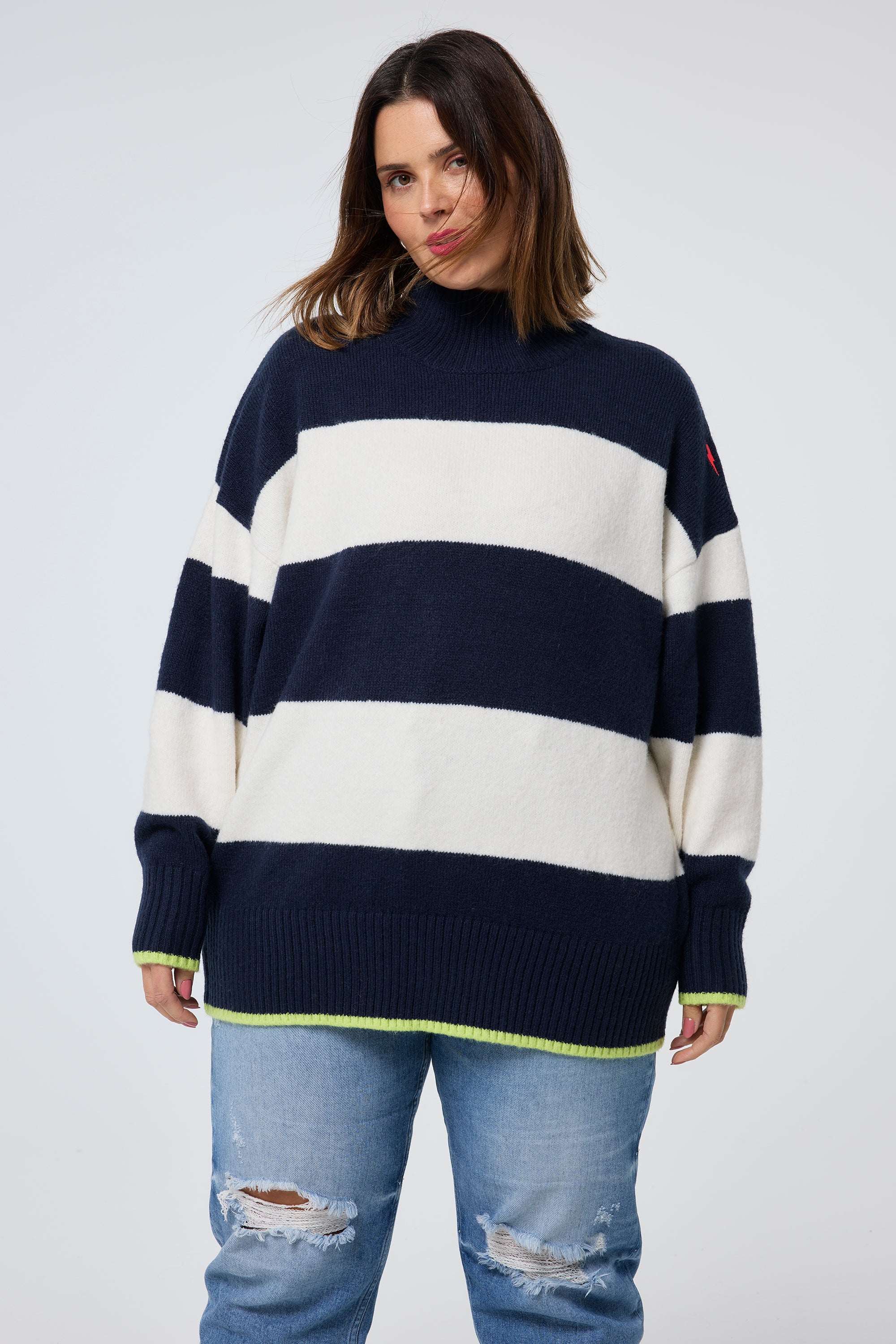 Scamp and Dude Navy with Ivory Stripe Oversized Turtle Neck Jumper | Model wearing a navy and ivory stripe turtleneck jumper paired with distressed jeans.