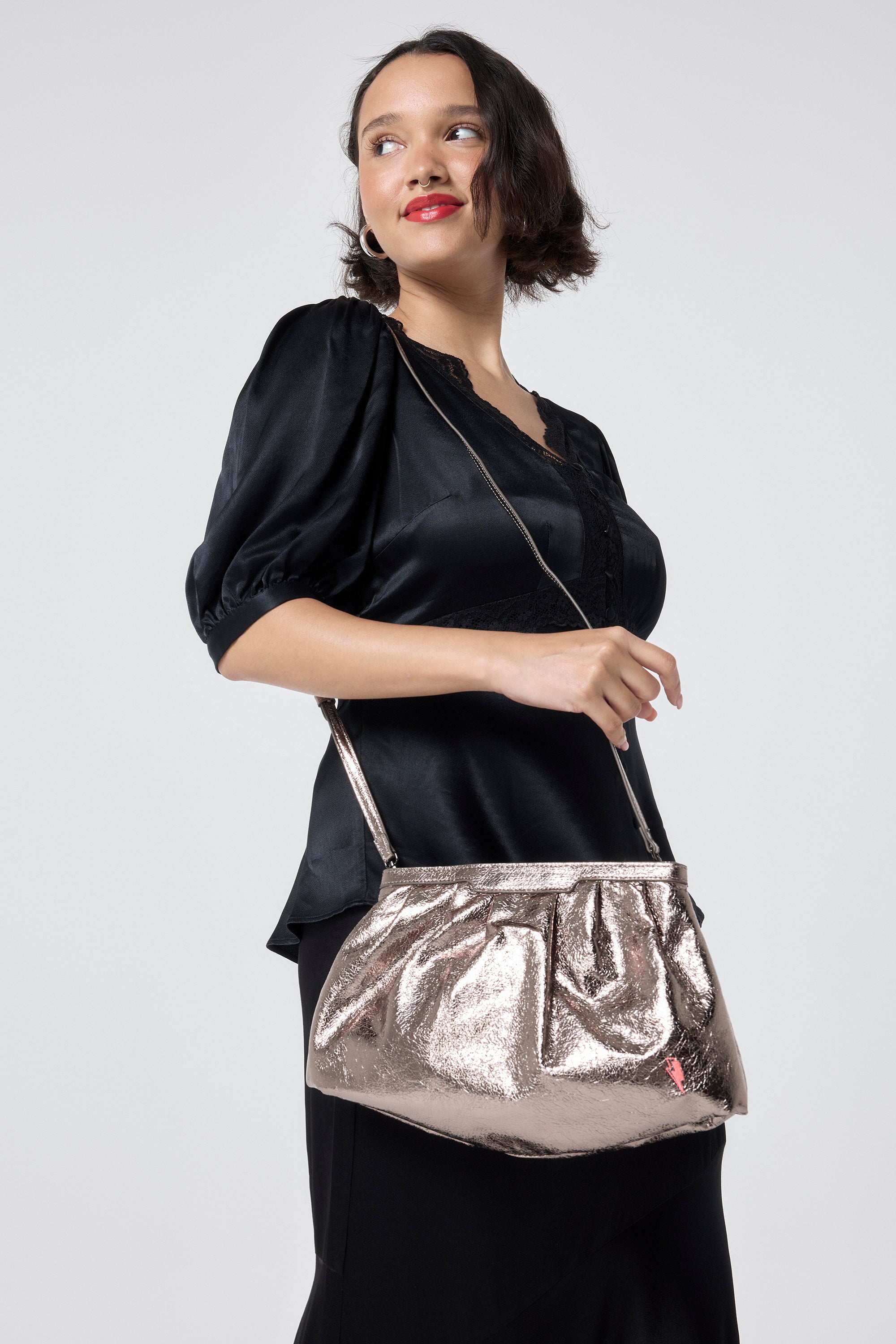 Scamp and Dude Pewter Metallic Clutch Bag | Model wearing a black satin top and skirt with a pewter metallic clutch bag.