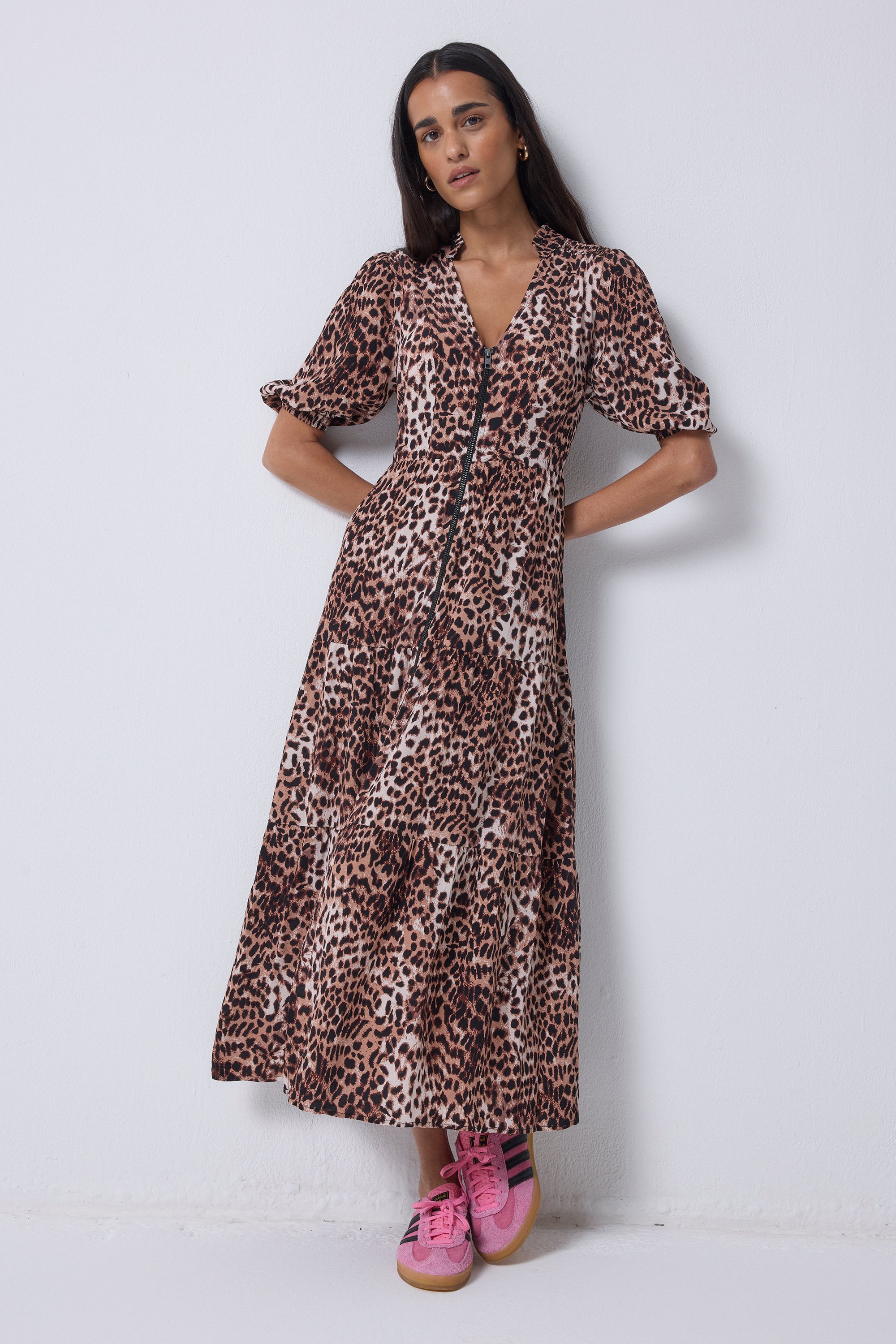 Scamp and Dude Neutral with Black Cheetah Zip Detail Tiered Midi Dress | Model wearing a neutral cheetah print midi dress with a zip front detail and short blouson sleeves, paired with pink trainers.