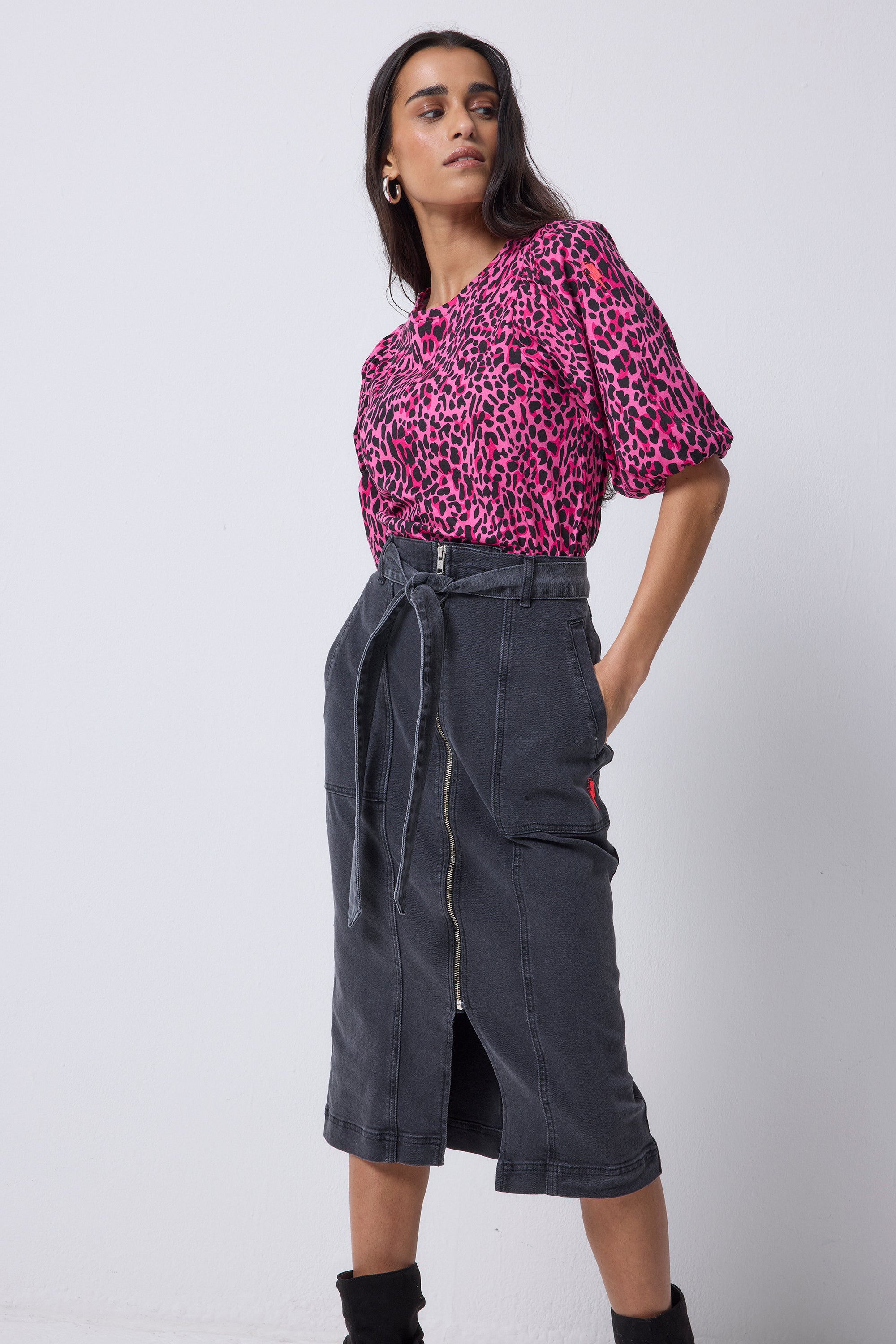 Scamp and Dude Washed Black Zip Detail Denim Midi Skirt | Model wearing a pink leopard puff sleeve t shirt with a black denim skirt and black boots.