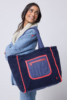 Scamp and Dude Navy Reversible Quilted Lightning Bolt with Borg Tote Bag | Model wearing a navy tote bag with borg detailing, paired with blue jeans and a denim jacket.