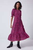 Scamp and Dude Pink Leopard Flute Sleeve Midi Dress | Model wearing a pink leopard print midi dress with black boots.