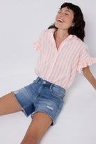 Scamp and Dude Distressed Denim Shorts | Model wearing a short sleeve stripe shirt with frill sleeves, paired with blue distressed denim shorts.