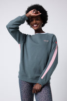 Scamp and Dude Khaki with Pink Colourblock Relaxed Sweatshirt | Model wearing a khaki sweatshirt with a pink stripe on the sleeve. Paired with khaki floral leopard leggings.