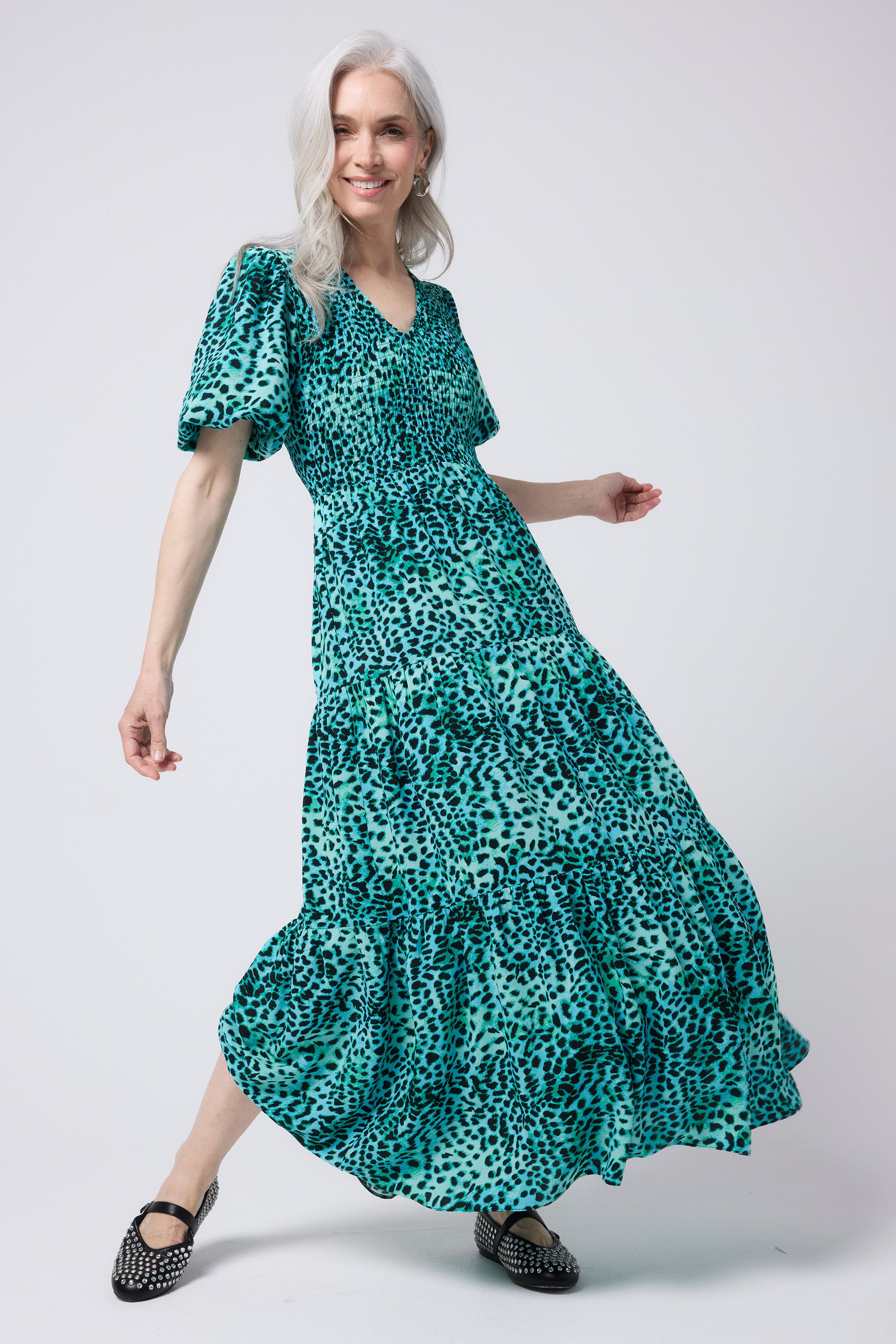 Scamp and Dude Green with Black Leopard Puff Sleeve Maxi Dress | Model wearing a green with black leopard print short sleeve maxi dress featuring a shirred bust and tiered skirt. Worn with black pumps.