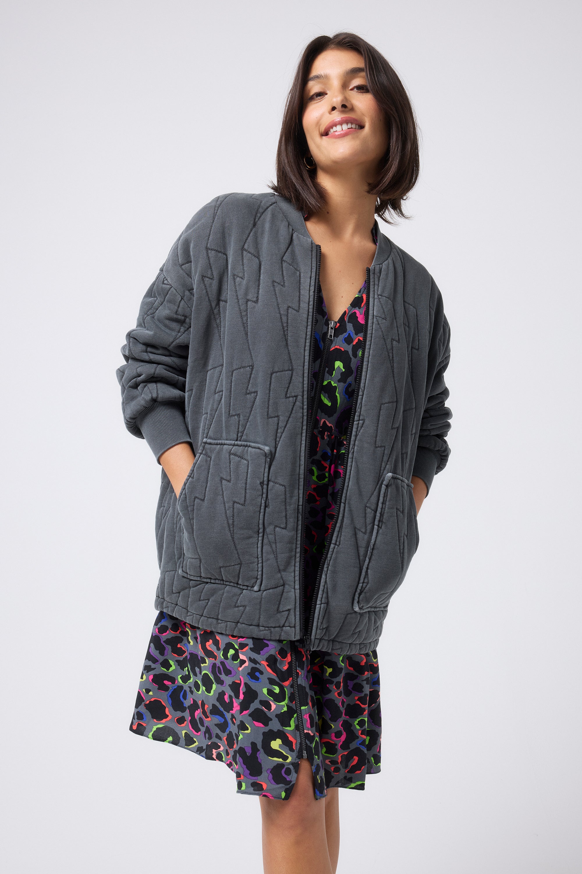 Scamp and Dude Washed Black Organic Cotton Quilted Lightning Bolt Oversized Bomber Jacket | Model wearing a grey rainbow leopard dress and washed black bomber jacket.