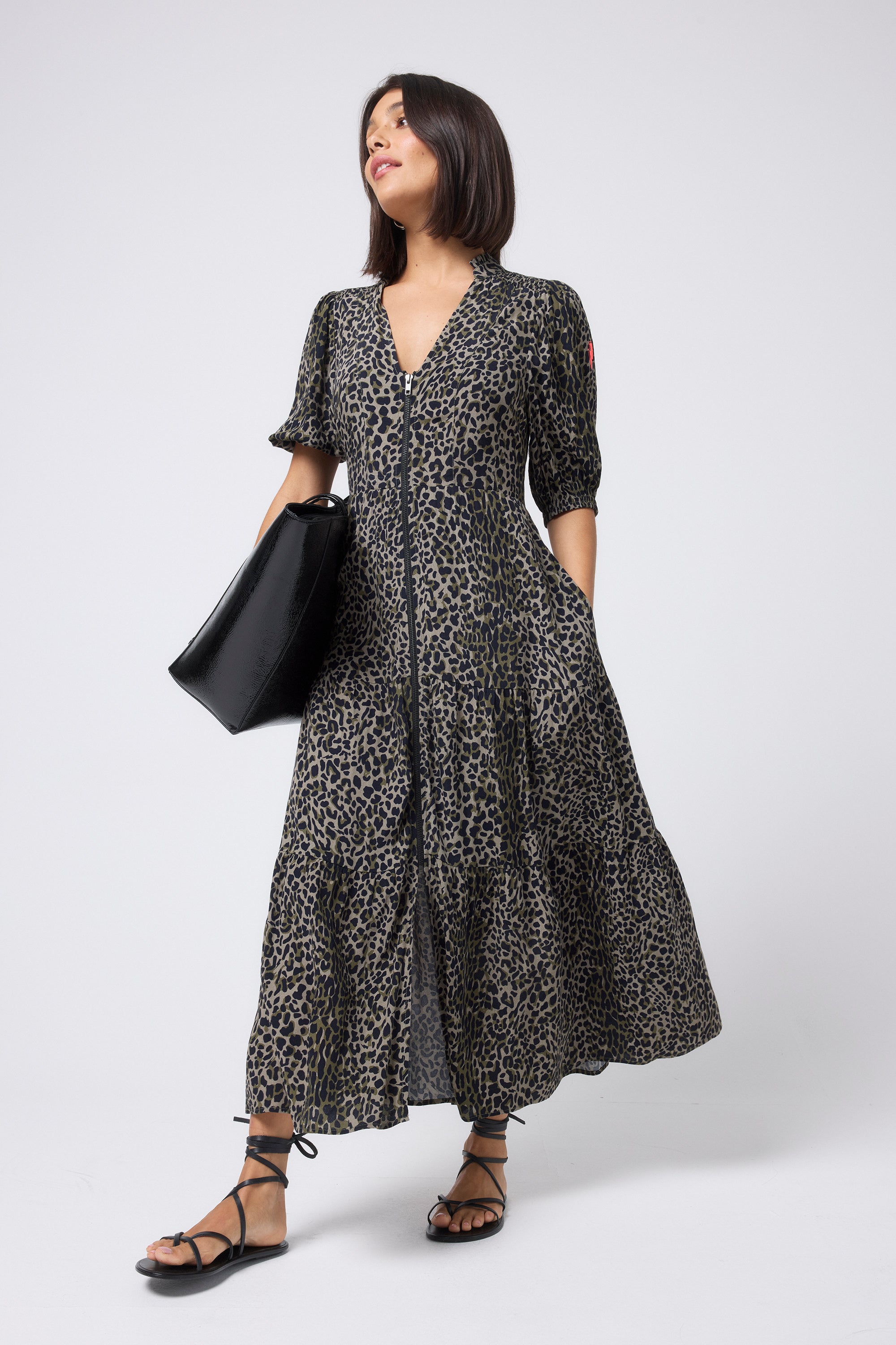 Scamp and Dude Khaki with Black Wild Leopard Zip Detail Tiered Midi Dress | Model wearing a short sleeve khaki zip front midi dress with black sandals and a black bag.