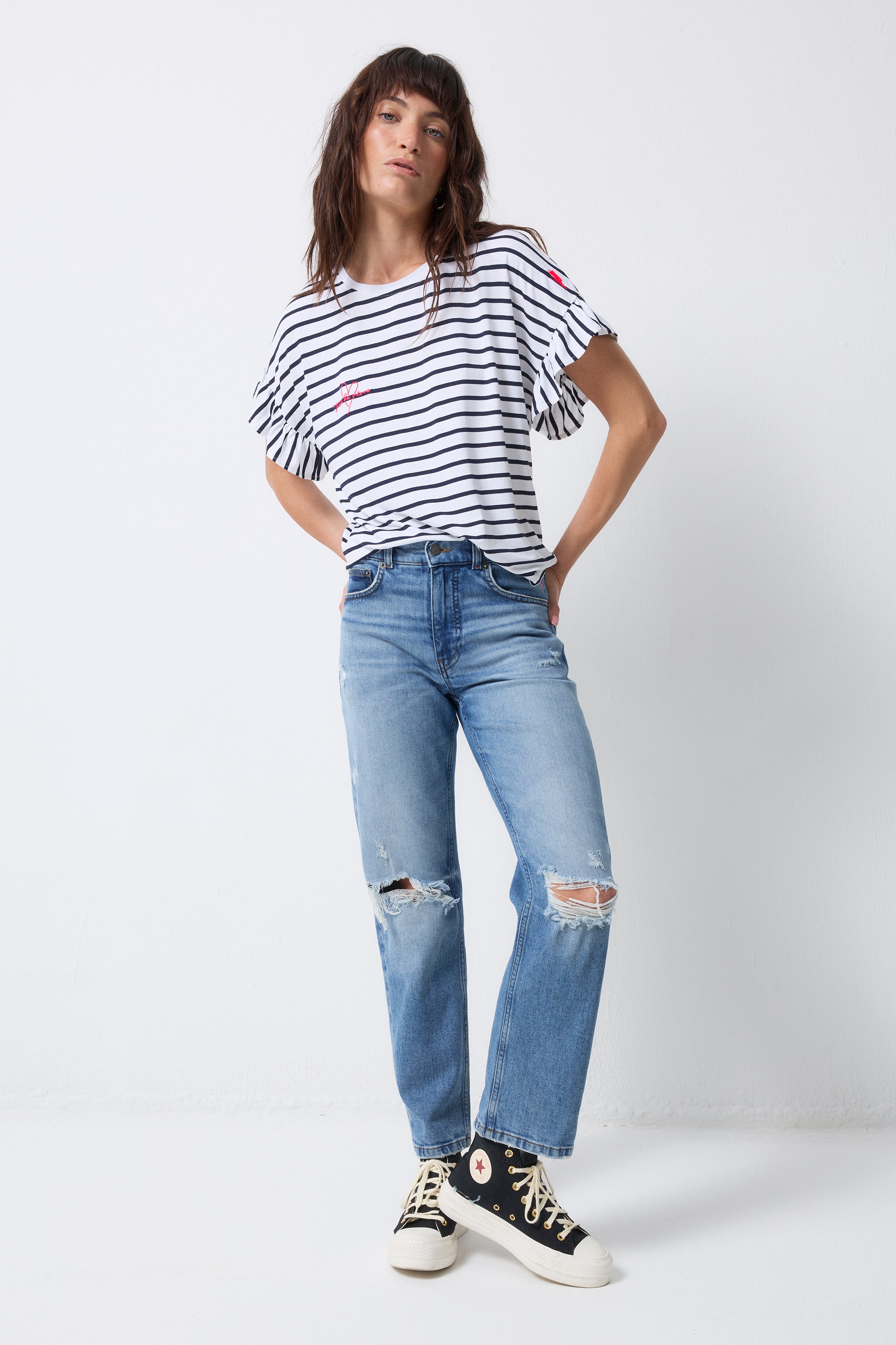 Scamp and Dude White with Navy Stripe Frill Sleeve T-Shirt | Model wearing a pair of distressed jeans with a round neck stripe t-shirt and frill sleeves.