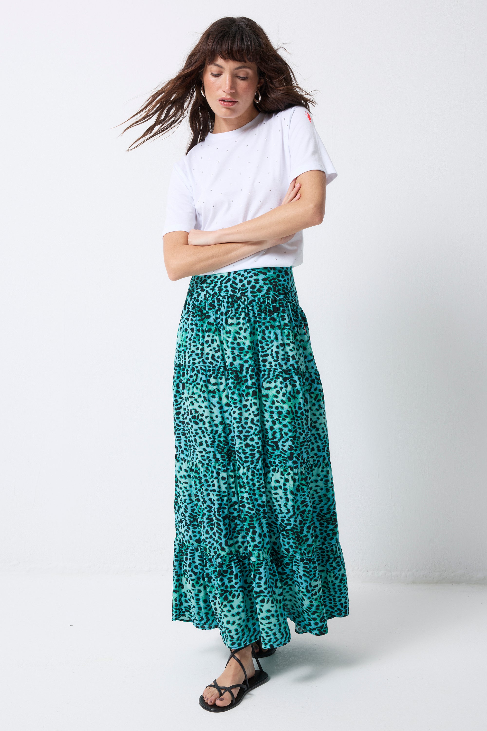 Scamp and Dude Turquoise with Black Wild Leopard Maxi Skirt | Model wearing a white t shirt and a turquoise maxi skirt with black leopard print. Paired with black sandals.