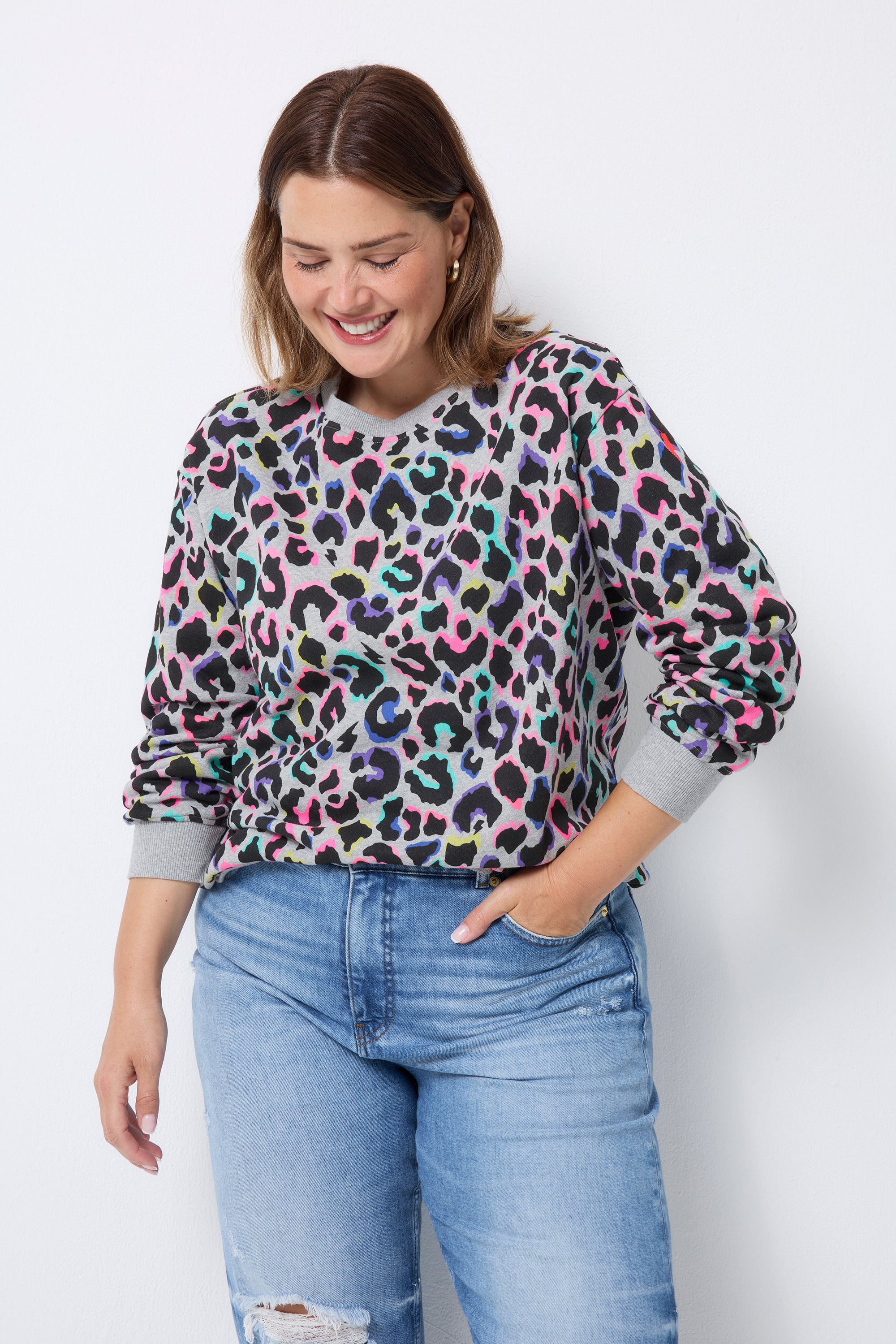 Scamp and Dude Light Grey with Rainbow Shadow Leopard Oversized Sweatshirt | Model wearing a light grey oversized sweatshirt with rainbow leopard print. Paired with distressed blue jeans.