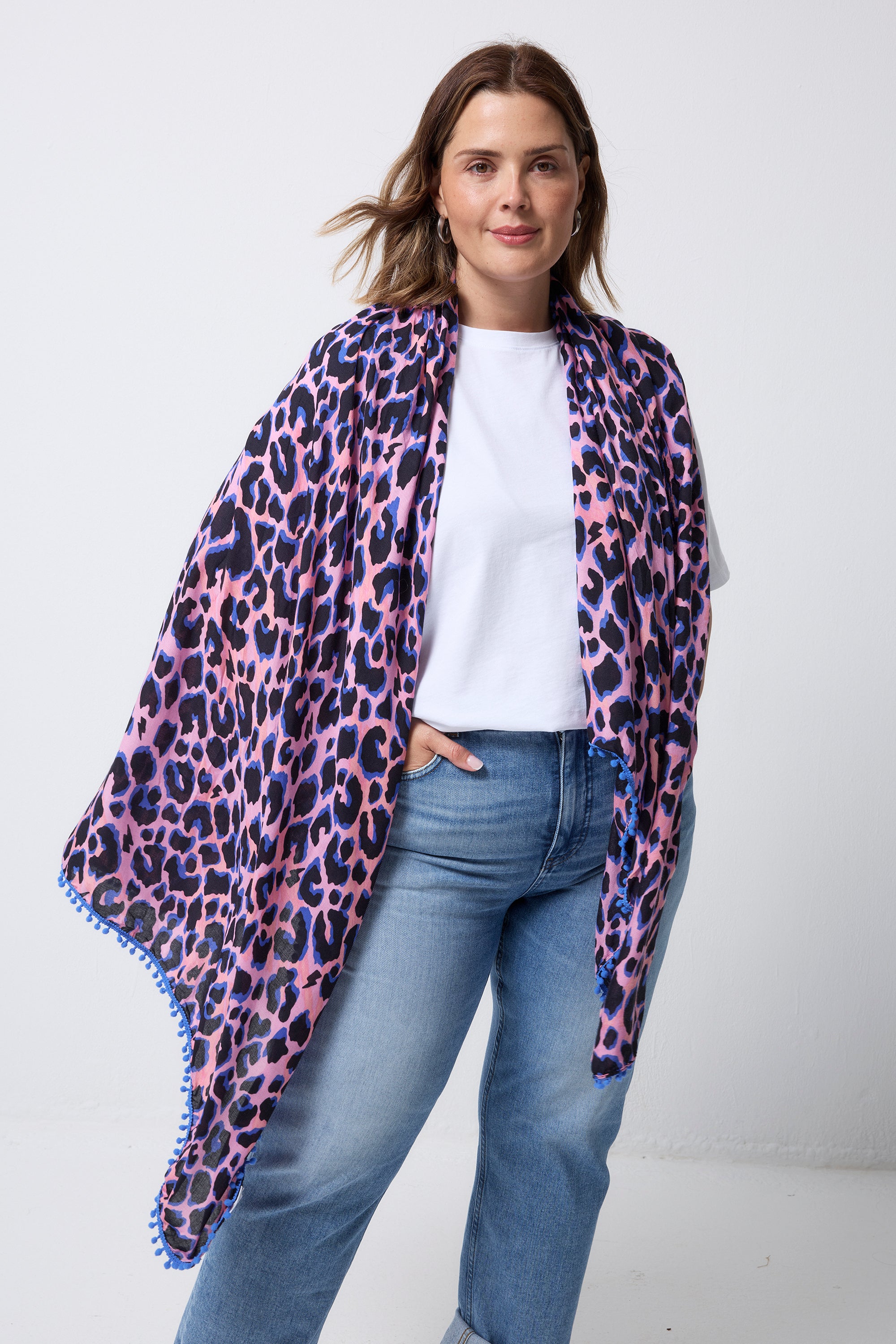 Scamp and Dude Pink with Blue and Black Shadow Leopard Charity Super Scarf | Model wearing a white t-shirt with blue jeans and a pink super scarf with all over blue and black leopard print.