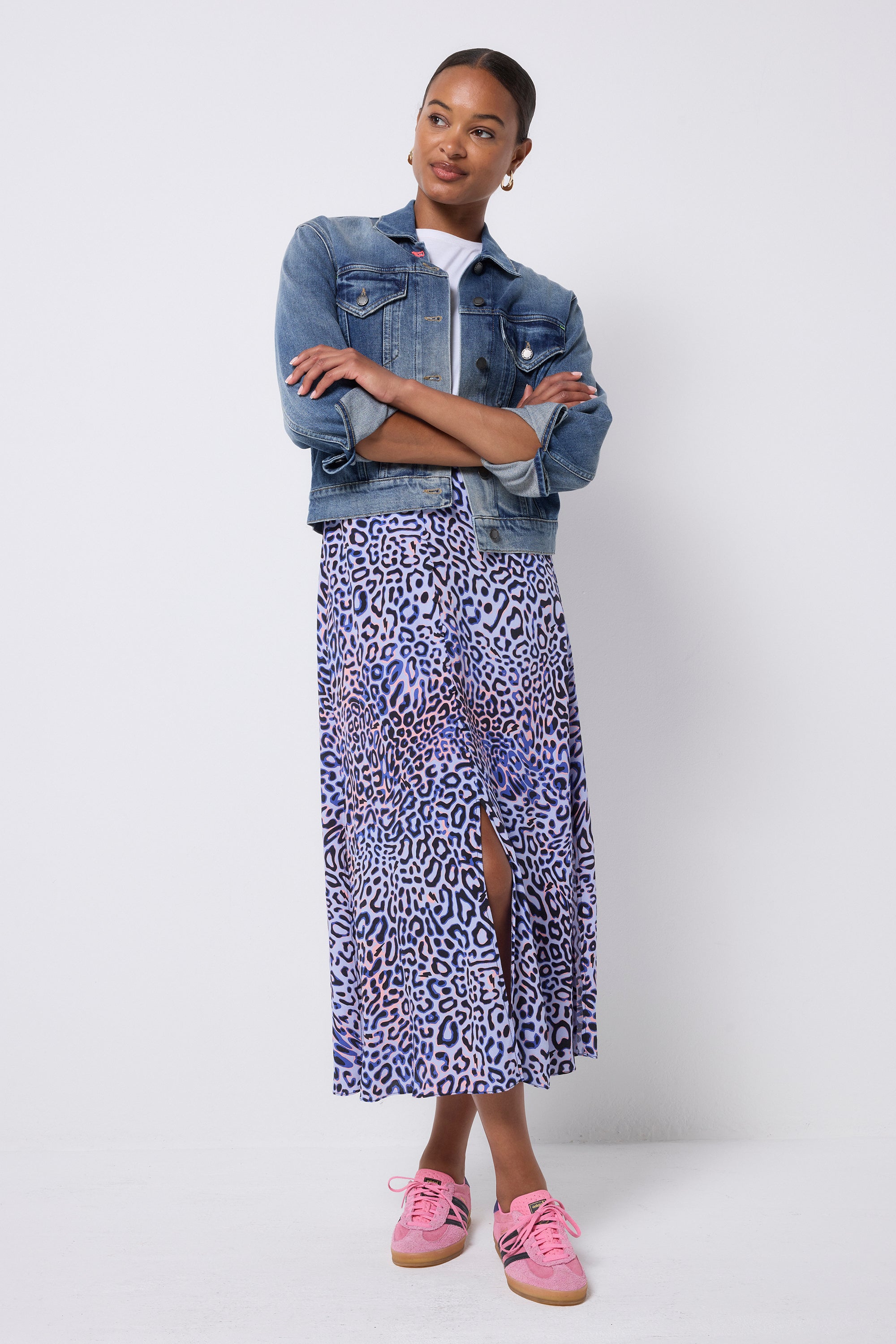 Scamp and Dude Lilac with Black and Pink Leopard Ray Button Through Skirt | Model wearing a white t-shirt with a blue denim jacket and a lilac leopard ray print midi skirt and pink trainers.