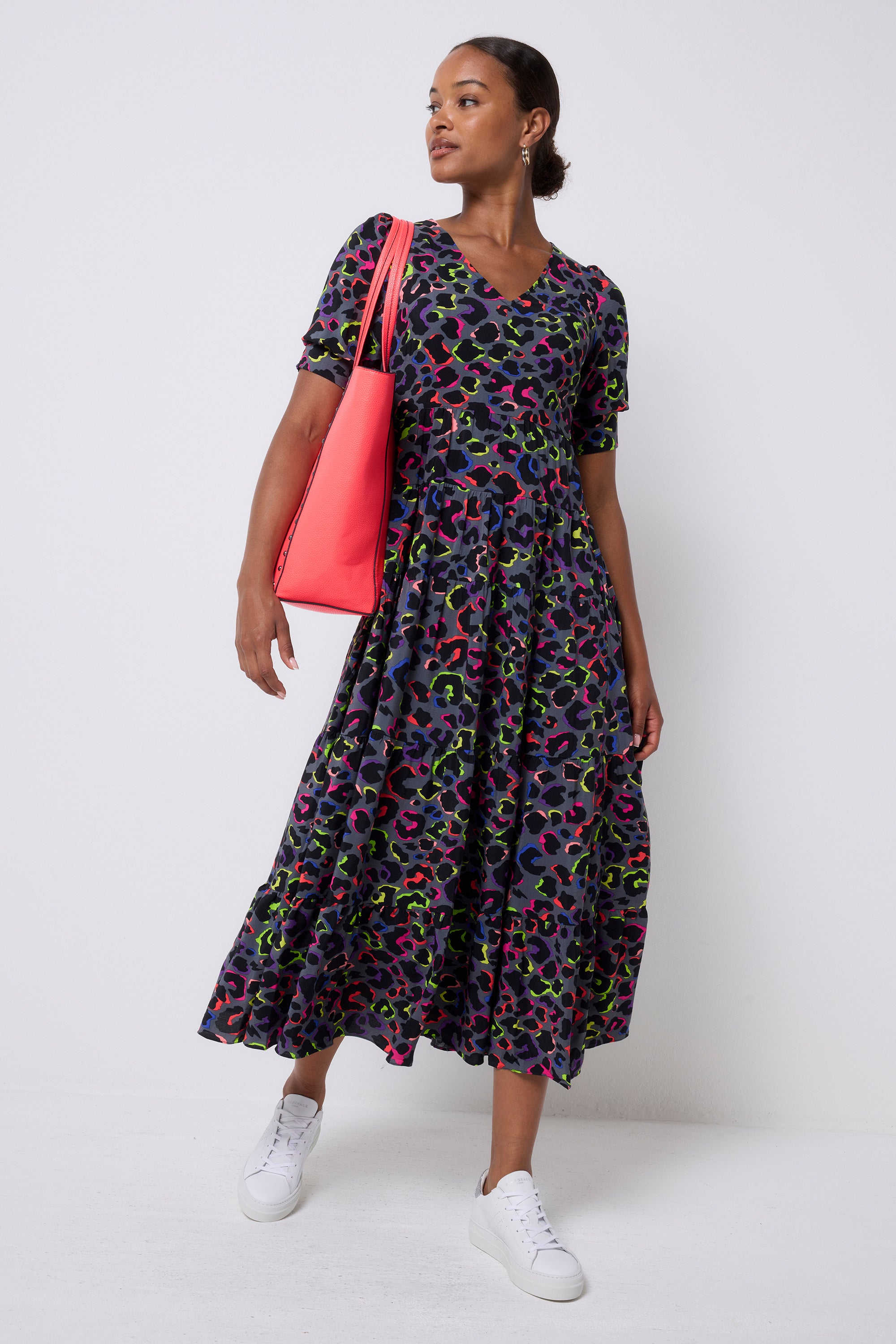Scamp and Dude Grey with Rainbow Shadow Leopard Maxi Dress | Model wearing a grey maxi dress with rainbow leopard print. Worn with white trainers and holding a neon coral tote bag.