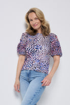 Scamp and Dude White with Blue and Pink Leopard Ray Pintuck Sleeve T-Shirt | Model with blonde hair wearing a white round neck t-shirt with blue and pink leopard ray print. The t-shirt has pretty pintuck sleeves. Worn with blue jeans.