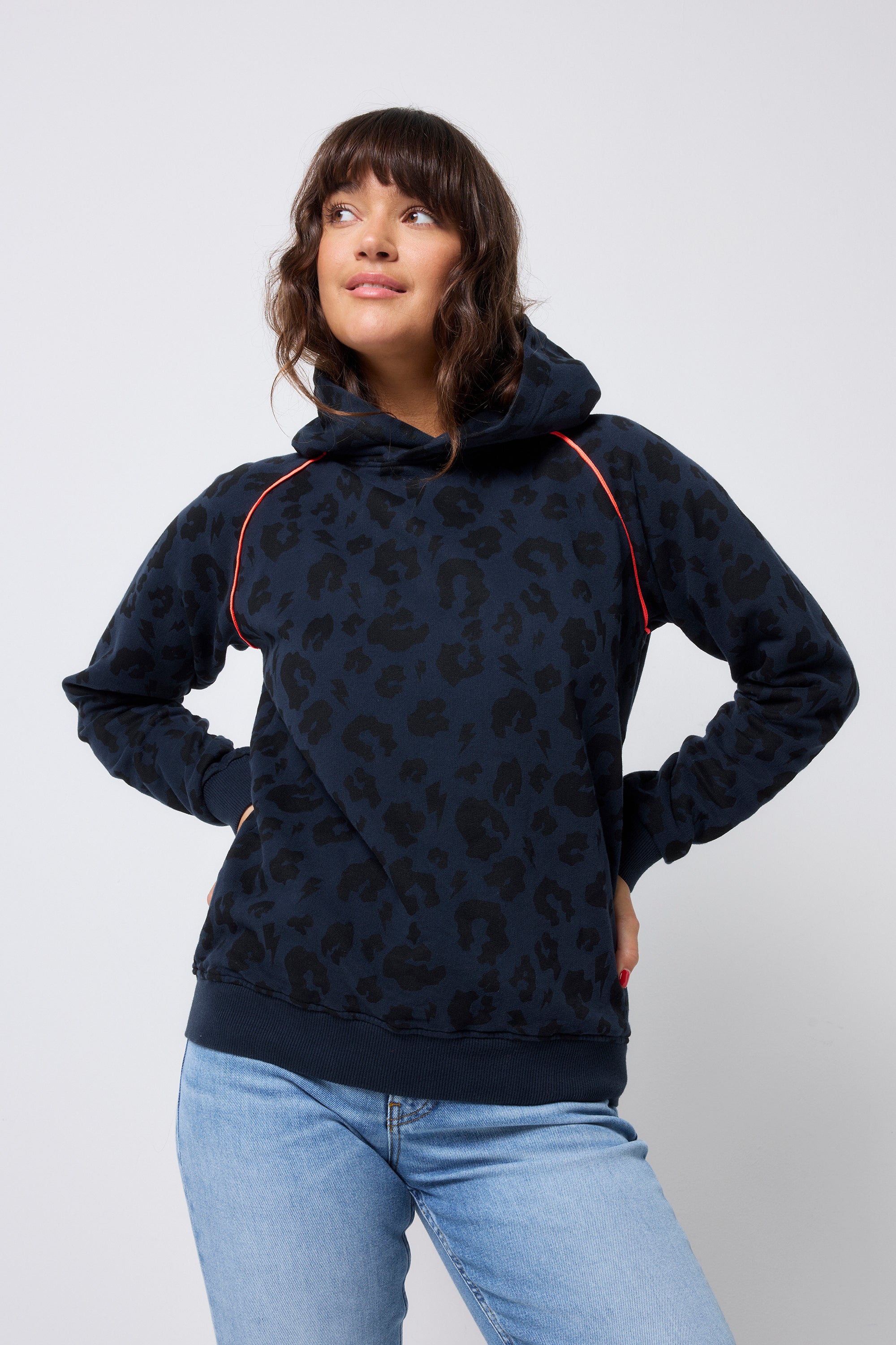 Scamp and Dude Navy Leopard Hoodie | Model wearing a navy leopard print hoodie with neon coral piping. Paired with blue jeans.
