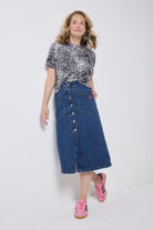 Scamp and Dude Authentic Indigo Button Front A-Line Denim Midi Skirt | Model wearing a blue denim button front skirt with a grey, white and black cheetah print t-shirt.
