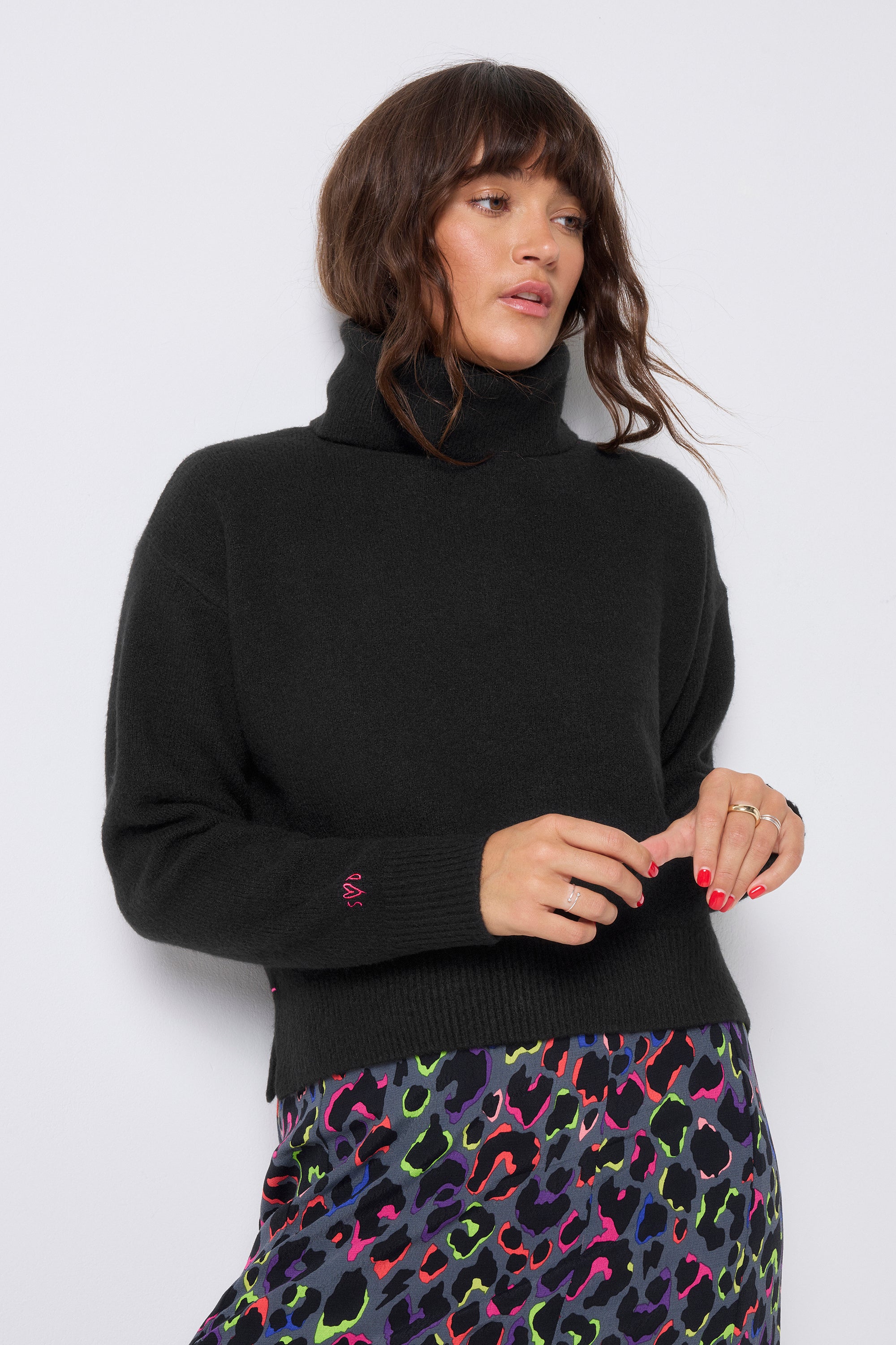 Scamp and Dude Black Turtleneck Knitted Jumper | Model wearing black turtleneck jumper with a grey rainbow leopard print skirt.