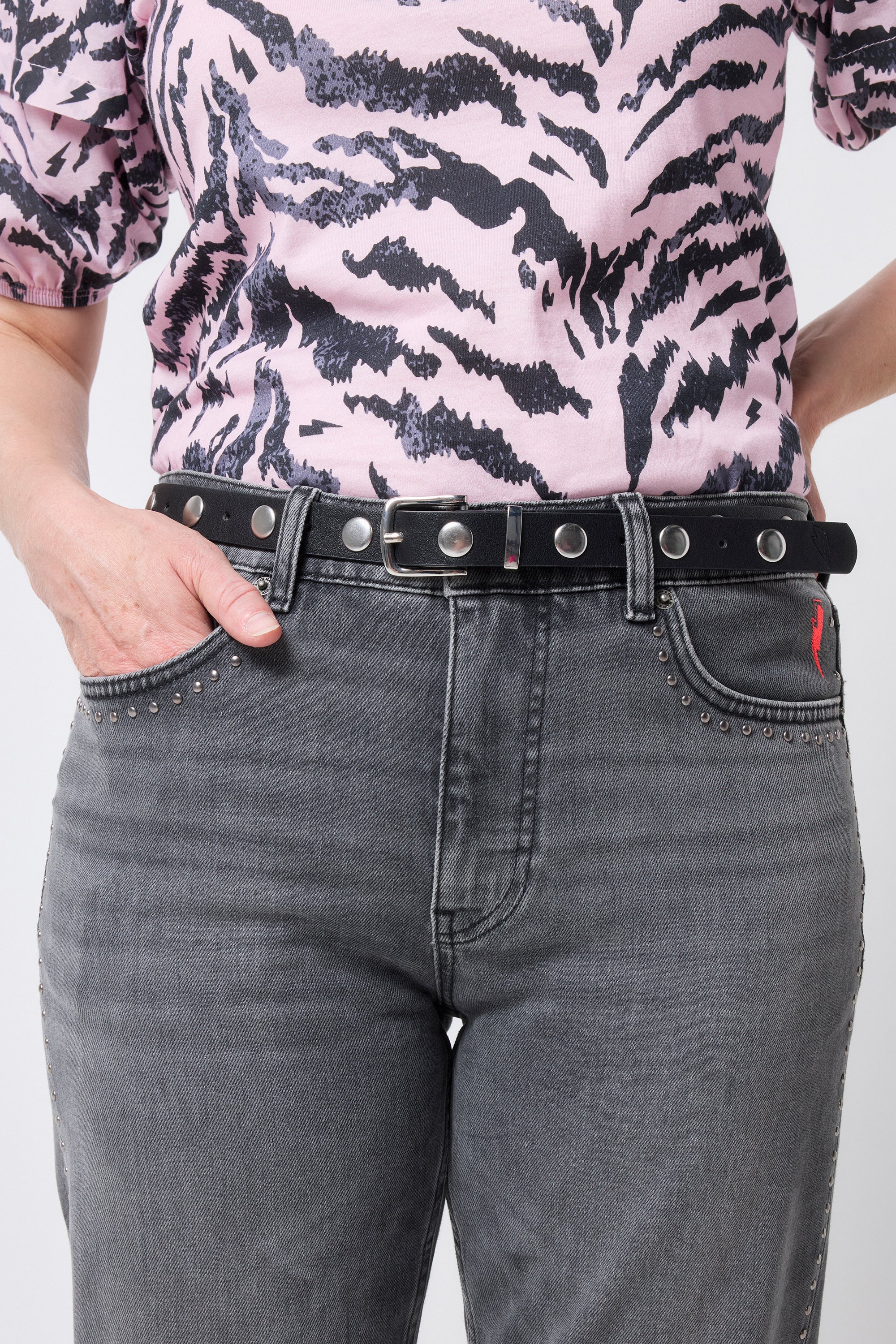 Scamp and Dude Silver Studded Black Belt | Model wearing a pair of grey jeans with a black belt with silver studs and a pink and black tiger print top.
