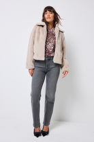 Scamp and Dude Cream Faux Fur Jacket | Model wearing washed black jeans with a faux fur jacket and neutral cheetah print top.