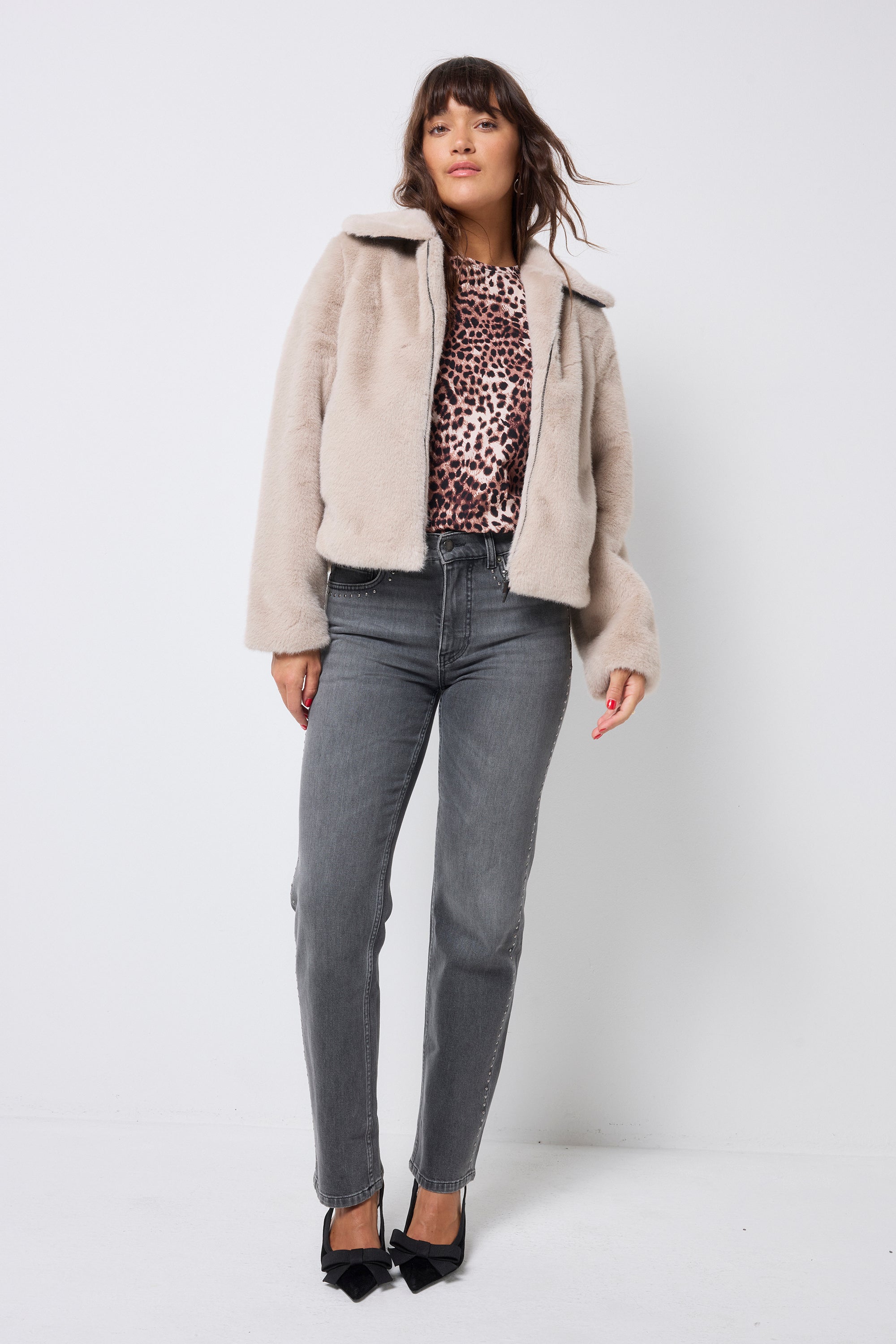 Scamp and Dude Cream Faux Fur Jacket | Model wearing washed black jeans with a faux fur jacket and neutral cheetah print top.