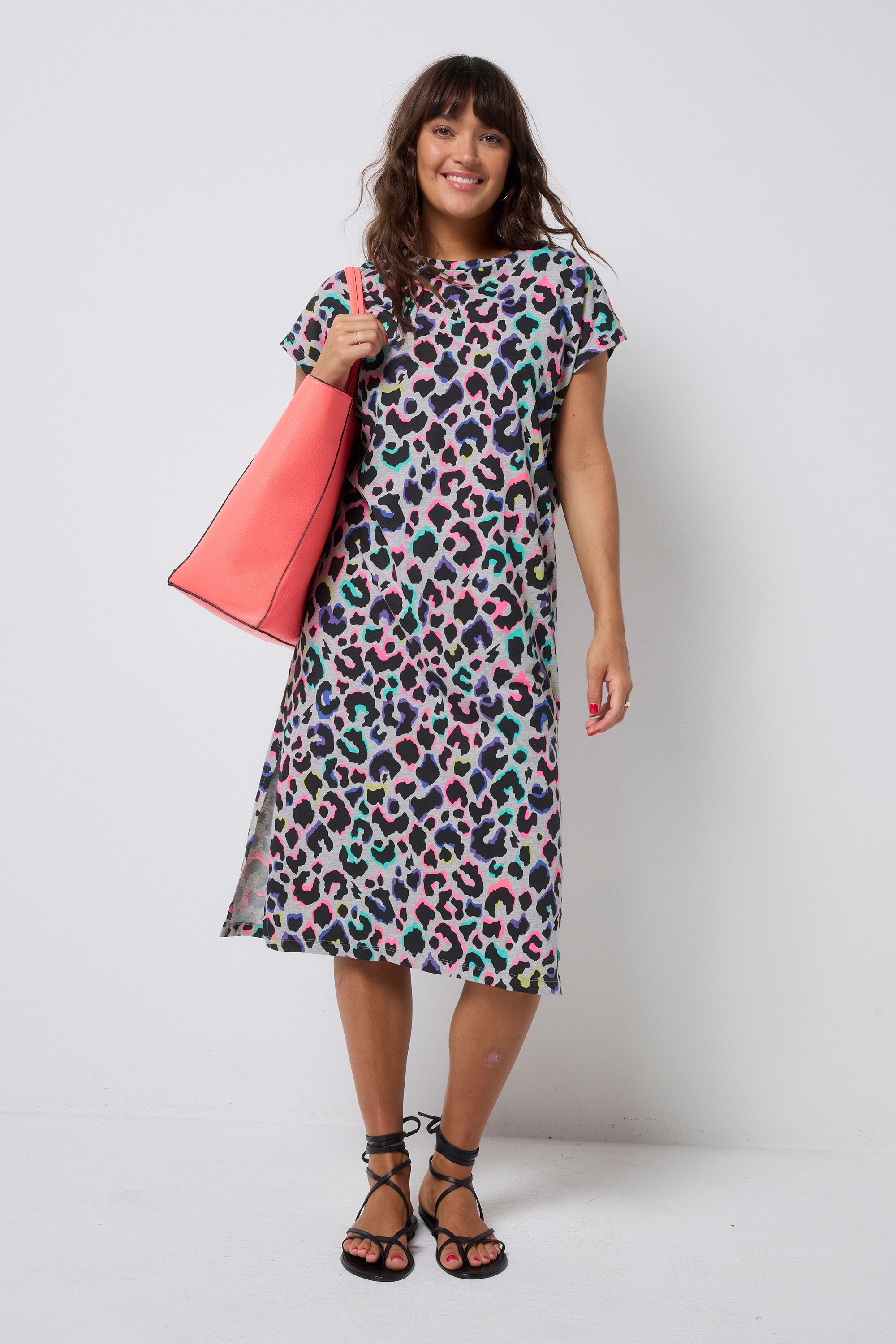 Scamp and Dude Grey with Rainbow Shadow Leopard Midi T-Shirt Dress | Model wearing a grey t-shirt dress with rainbow leopard print. Worn with a coral bag and black sandals.