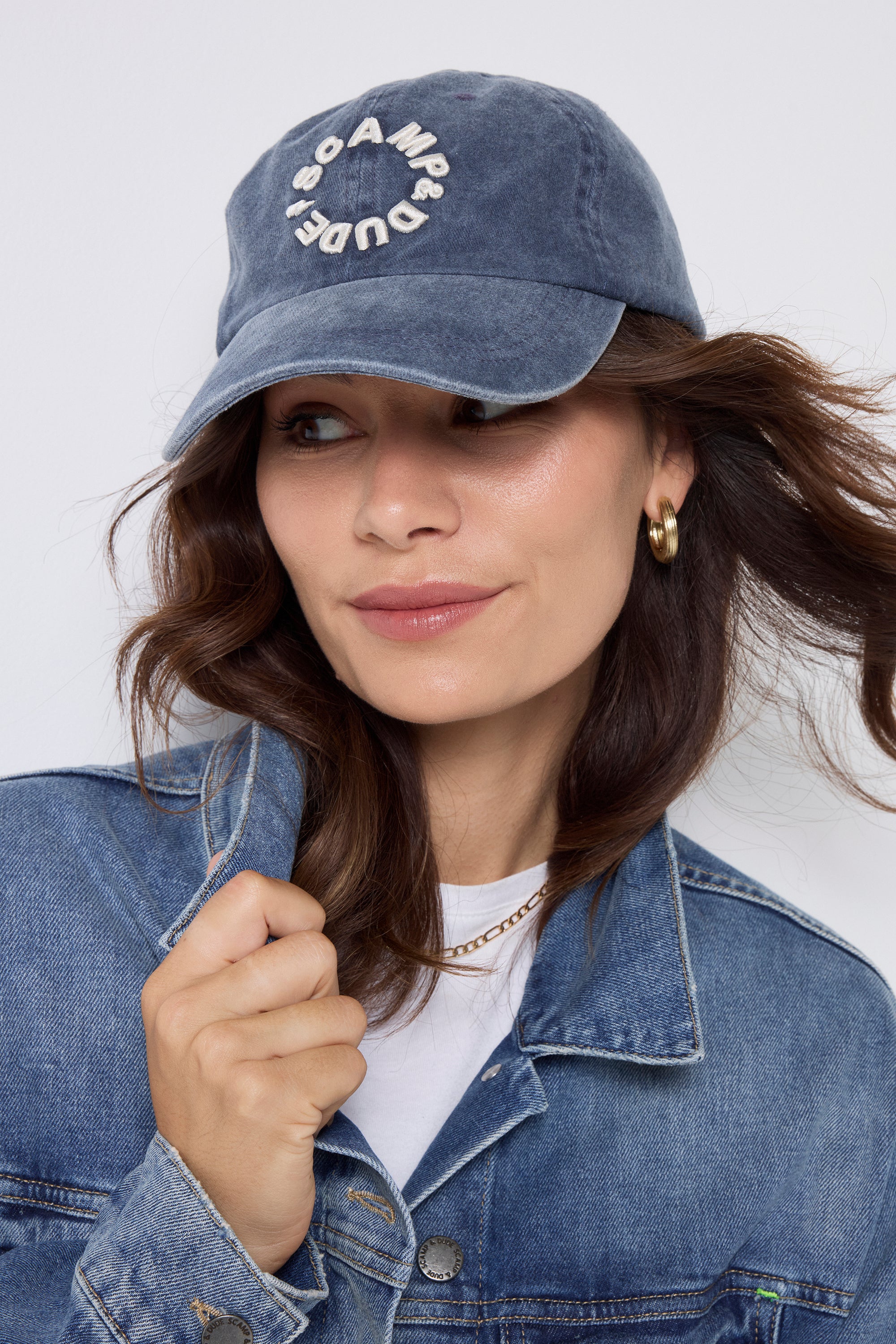 Scamp and Dude Washed Blue Graphic Logo Cap | Model wearing a blue denim jacket with a white t-shirt and a blue cap.