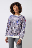 Scamp and Dude Ivory with Blue and Pink Leopard Ray Oversized Sweatshirt | Model wearing a crew neck sweatshirt with blue and pink leopard ray print. Worn with grey studded jeans.